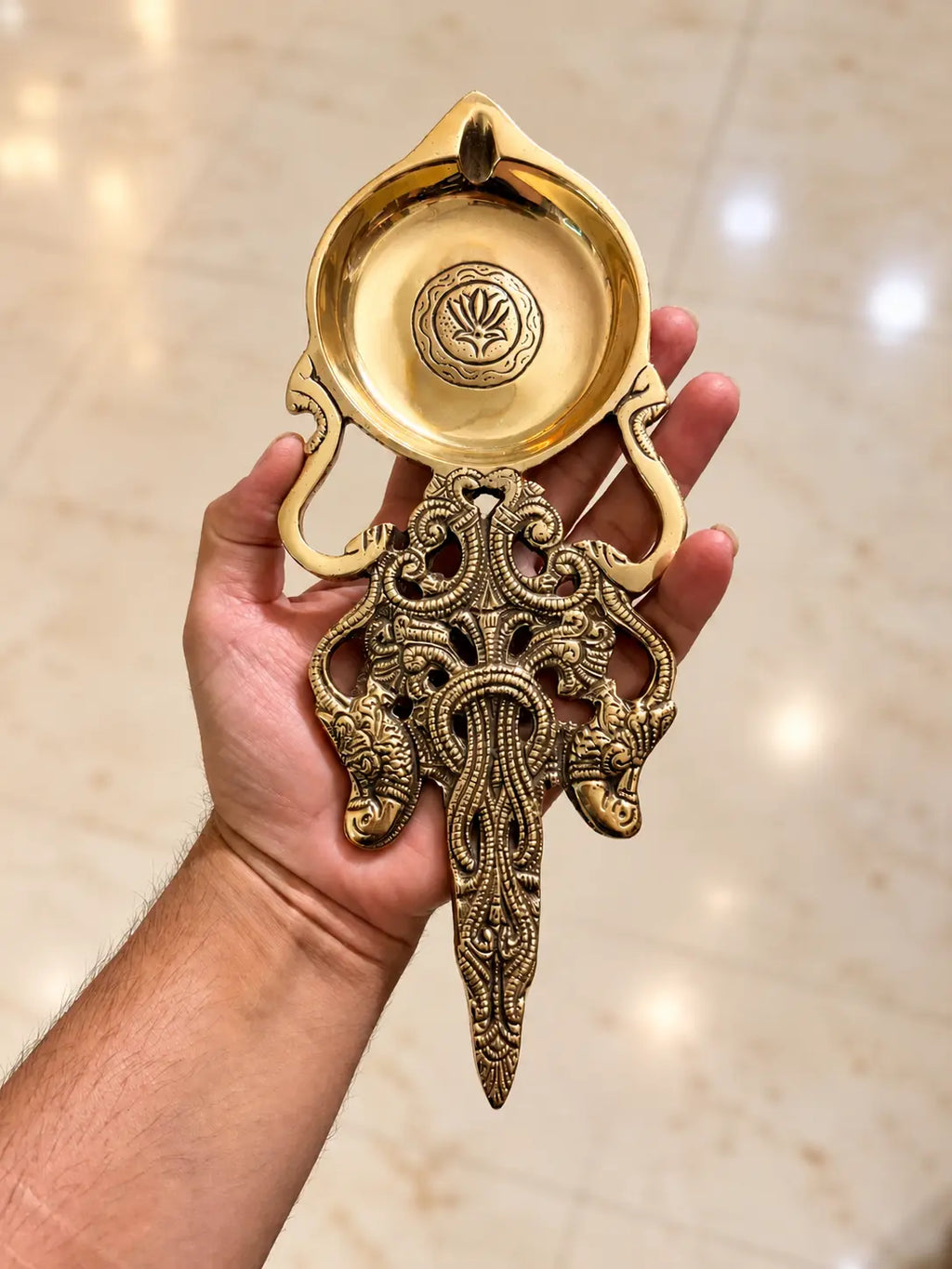 brass pooja spoon in hand