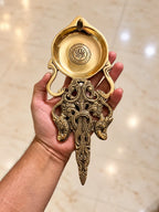 brass pooja spoon in hand