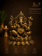 A brass Ganesha statue displayed on a dark brown background with a lit candle and a plant in the background. The image includes branding text for 'Yashrahomes' and feature icons for premium brass, innovative design, artisan crafted, and timeless elegance.