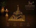A brass miniature temple model of Jay Shri Ram's temple on a square base, displayed on a dark brown background with decorative brass lamps and a plant. The image includes branding for Yashrahomes and feature icons at the bottom.